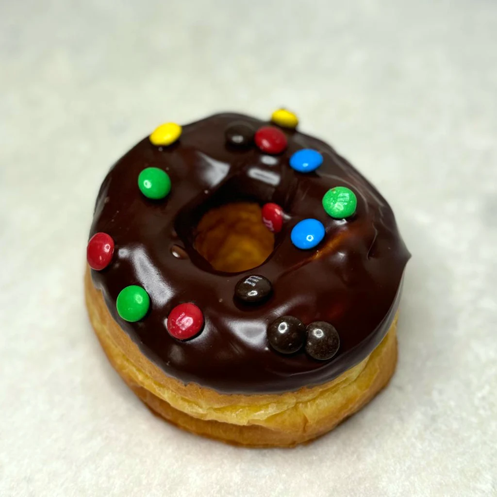 Chocolate frosted ring donut with M&M